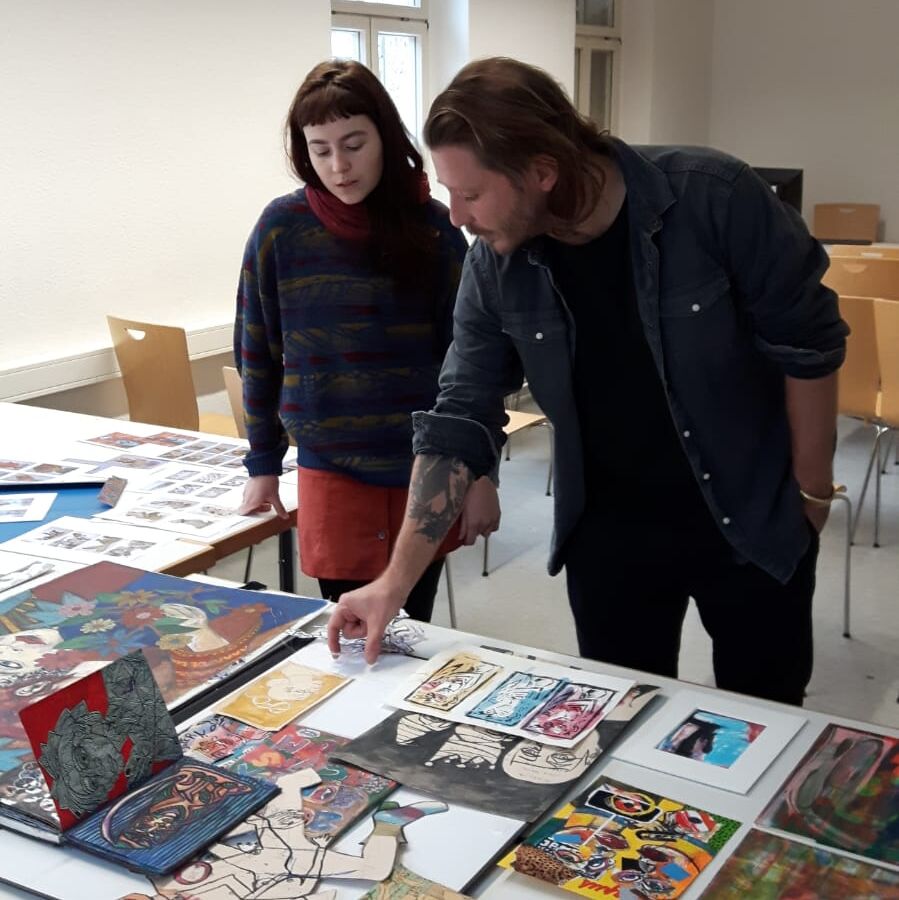 Führung in der Hochschule. Menschen schauen Kunstwerke an.
