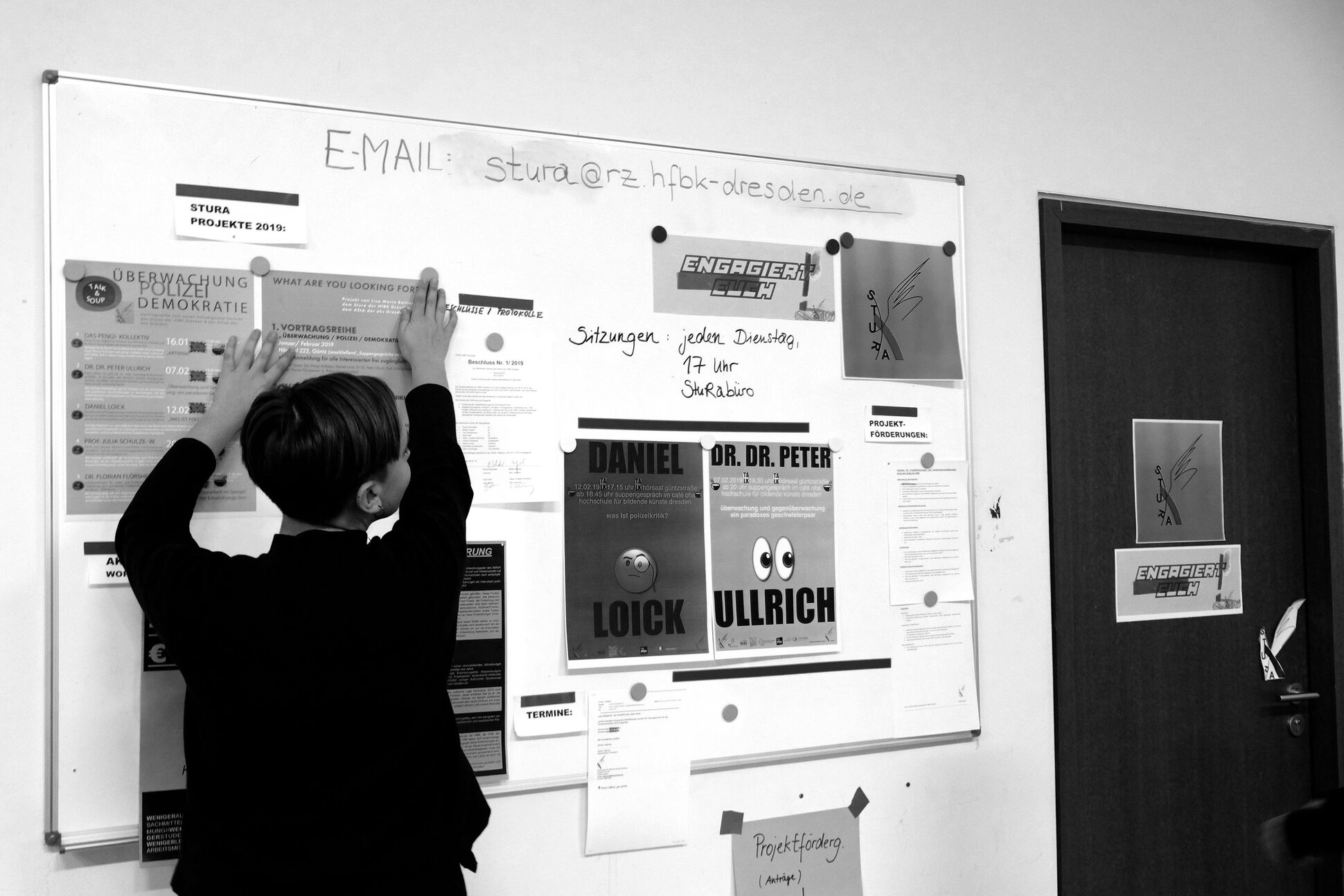 Eine Mitgliederin des Studentenrats hängt die Plakate an.