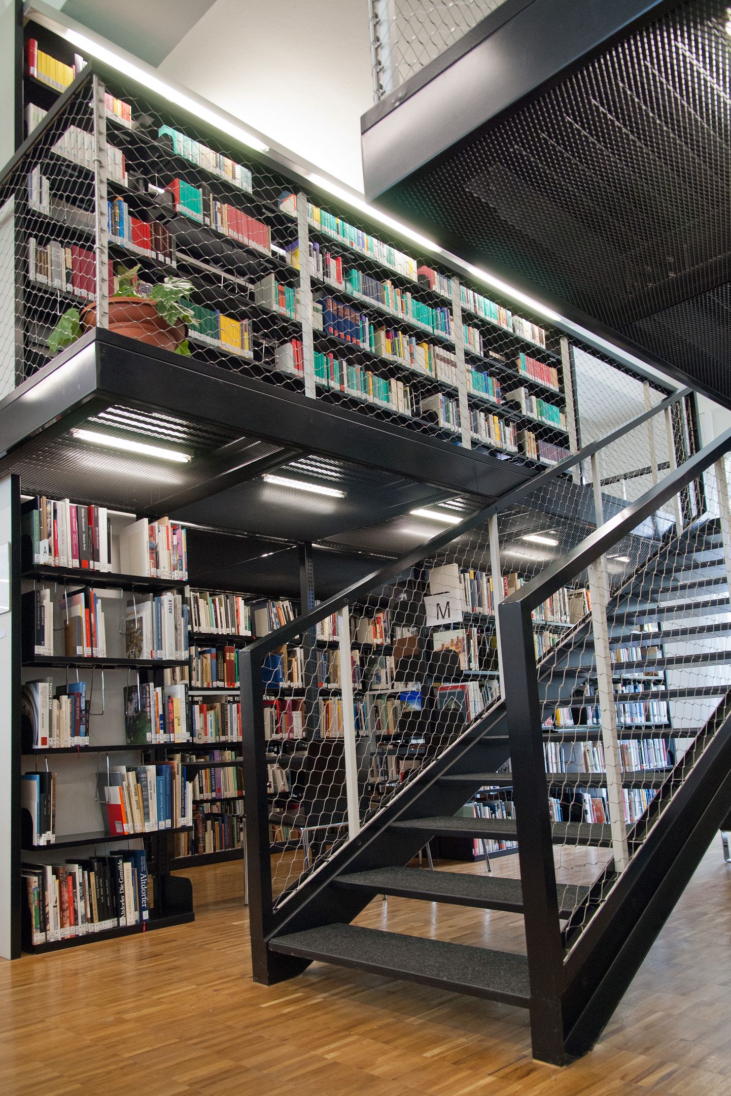 Bibliothek der Hochschule. Mehrere Bücherregale und eine Treppe.