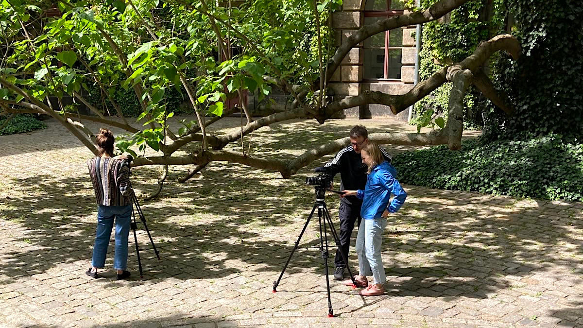 Personen mit einer Kamera im Hof der HfBK