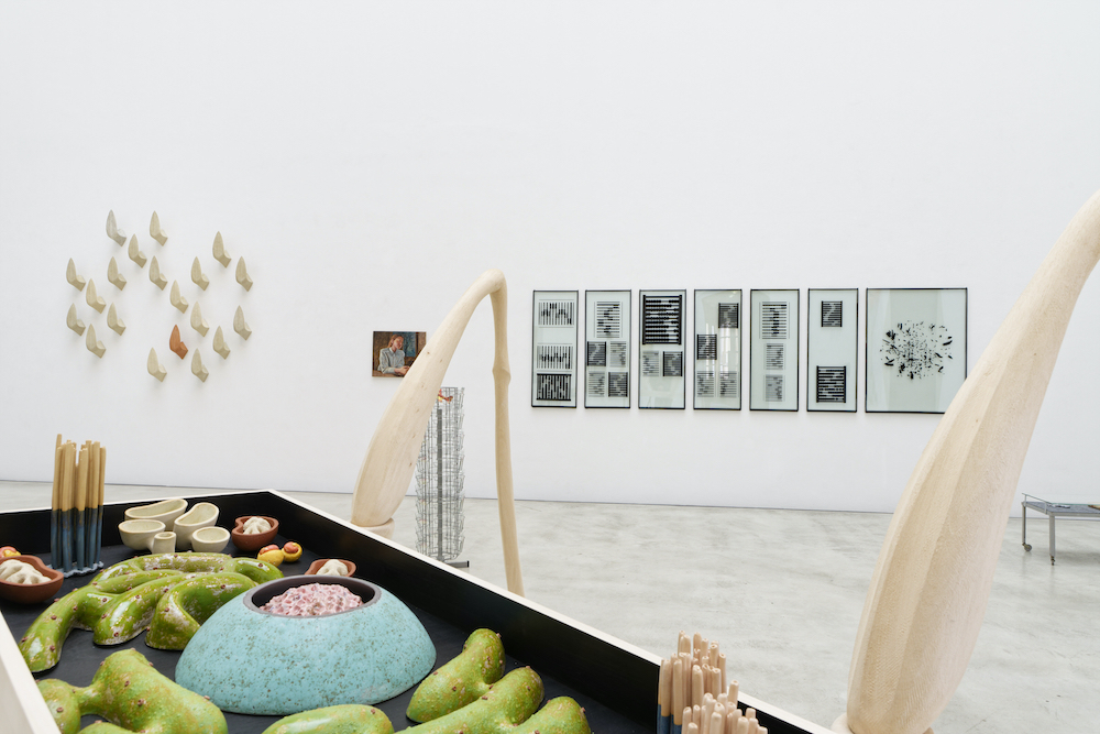 Ausstellungsansicht. Holz und Keramikskulptur im Vordergrund, dahinter Malerei.